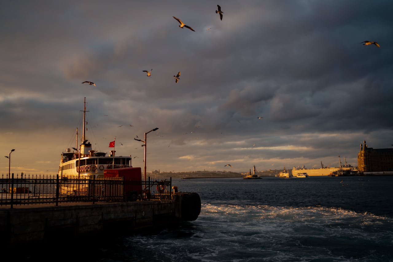 Ferry docked in Istanbul at sunset with dramatic skies and seagulls.